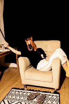A person wearing a horse mask lounging on an armchair indoors, creating a quirky and humorous scene.